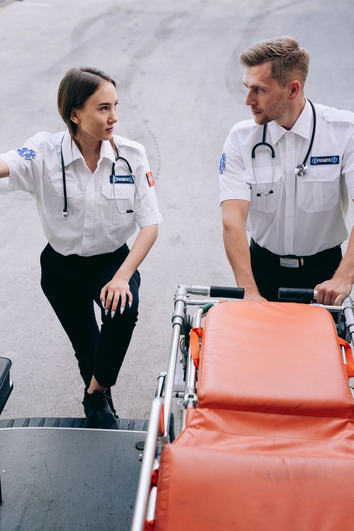 Two paramedics with a gurney preparing for an emergency response outdoors.